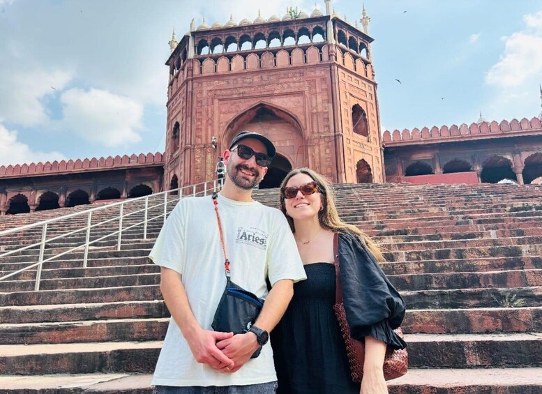 A man and a woman standing in front of a large, historic building with a grand staircase. 2