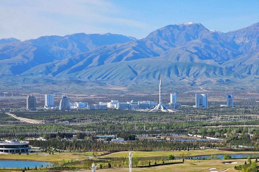 A cityscape with a prominent tower, a large body of water, and mountains in the background. 2