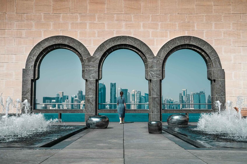 A woman standing in front of three arches overlooking a city skyline. 5