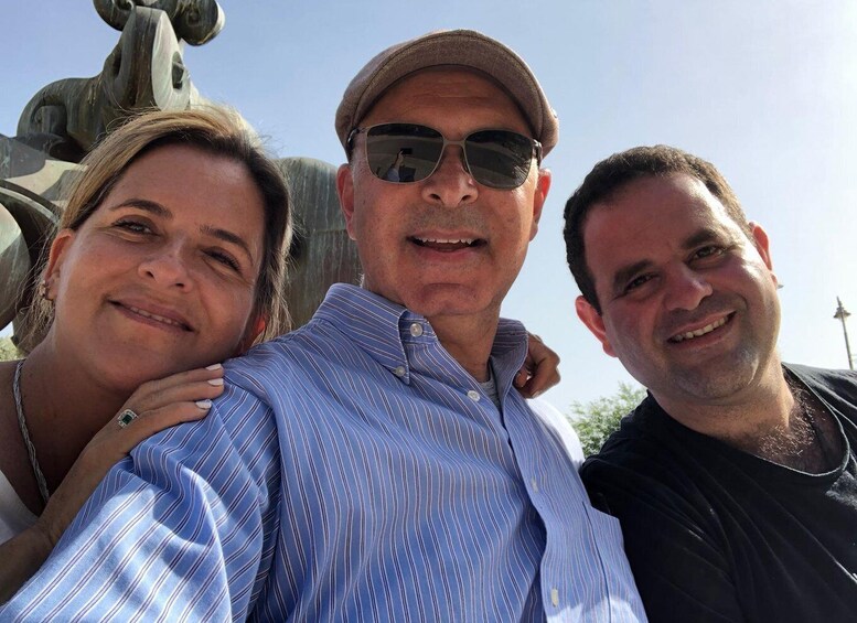 Three people posing in front of a sculpture. 2