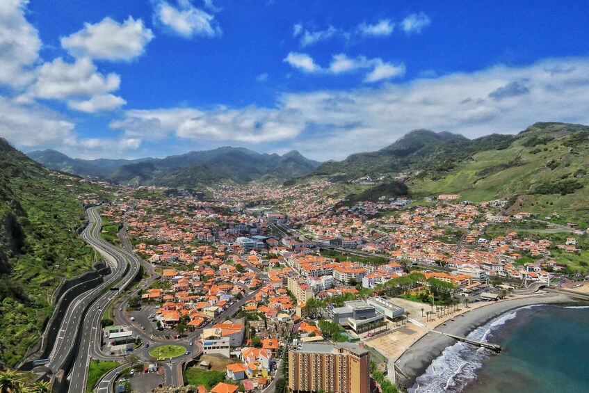 A coastal city with winding roads, red-roofed buildings, and a beach. 2