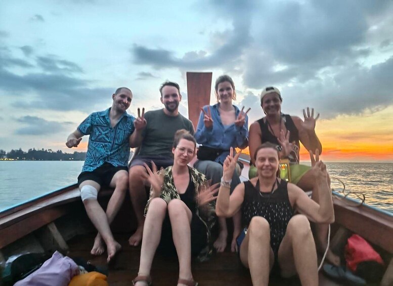 A group of people on a boat with a sunset in the background. 2