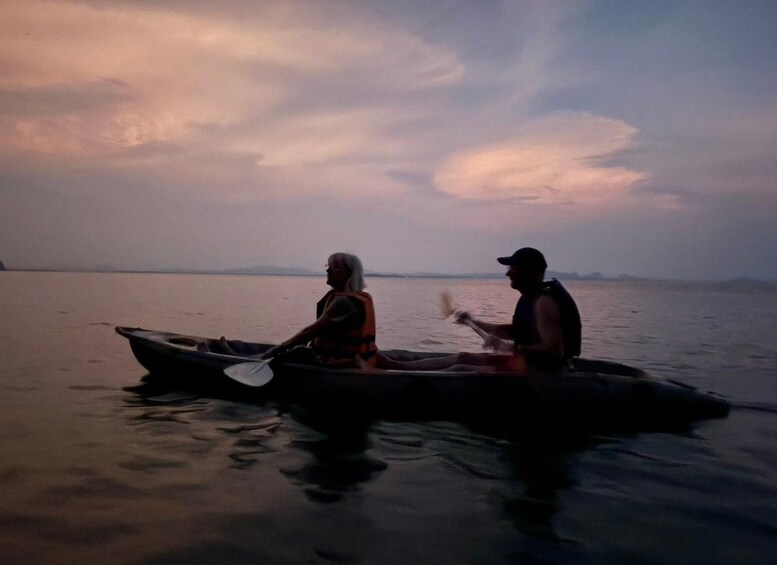 Twee personen in een kano op een rustig wateroppervlak tijdens de zonsondergang. 4