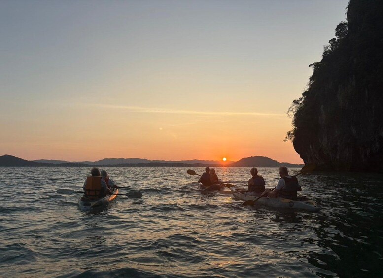 Mensen kajakken op een rustig wateroppervlak tijdens de zonsondergang. 3