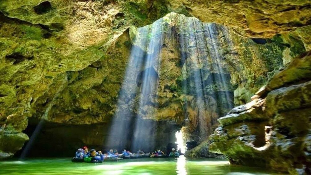 Un grupo de personas haciendo rafting en una cueva con una cascada. 5