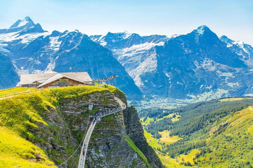 A mountain lodge on a cliff with a cable car and a valley below. 5