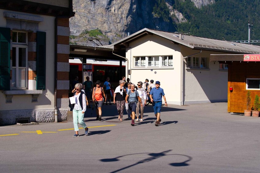 A group of people walking towards a building with a mountain backdrop. 2