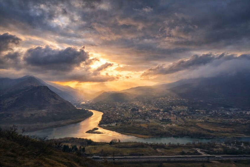 A river winding through a valley with mountains in the background and a town along the riverbanks. 5
