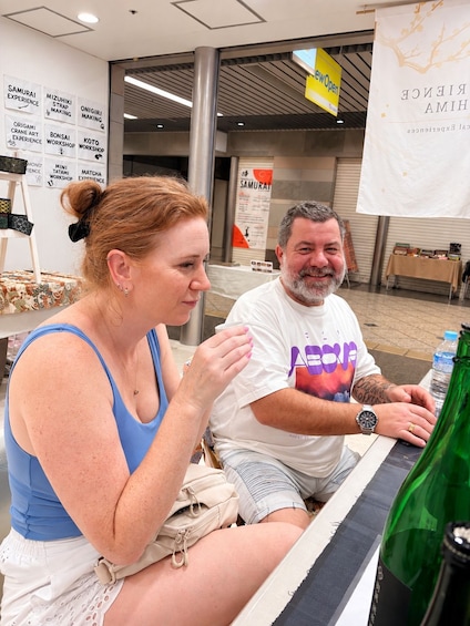 Two people sitting at a table with a green bottle in front of them. 3