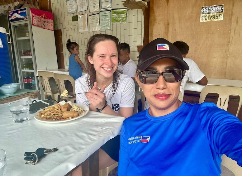 Two people sitting at a table with a plate of food, a drink, and keys on the table. 4