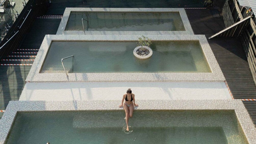 A person in a bikini walking on a tiered pool structure. 1
