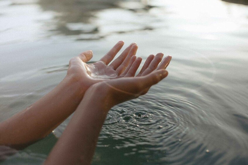 A pair of hands reaching into calm water. 2