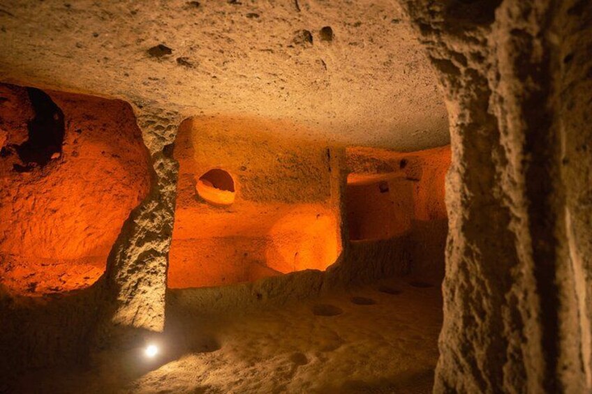A cave with orange lighting, rock formations, and a small hole. 1