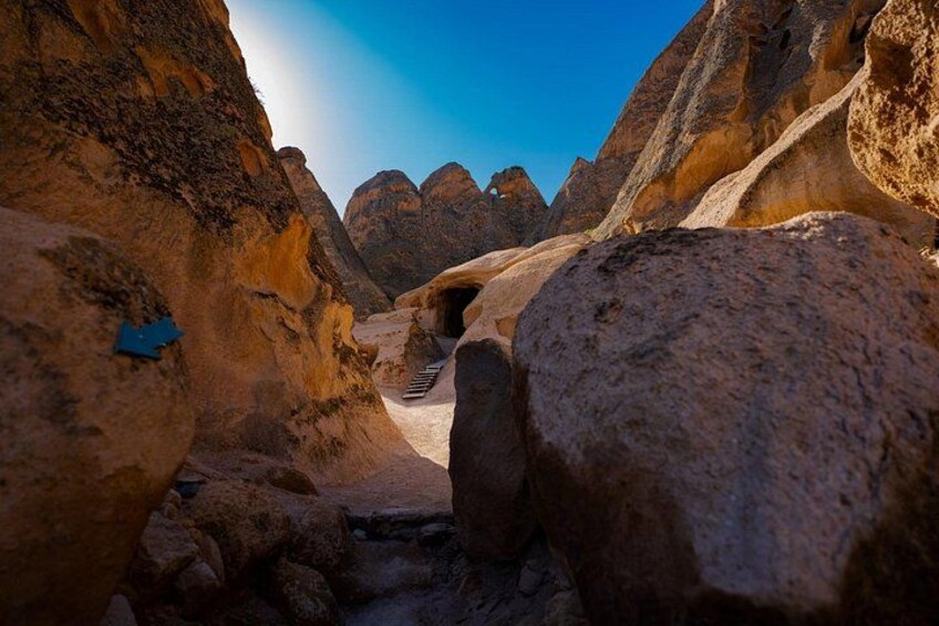 A narrow canyon with large boulders and a clear sky. 2