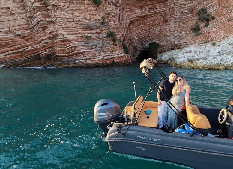 A boat named 'ITHACA 550' with a Yamaha outboard motor, anchored near a rocky cliff with layered sedimentary rock formations. 2