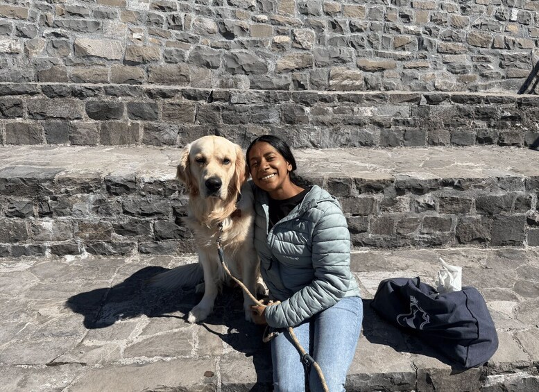 A person with a dog in front of a stone wall. 4