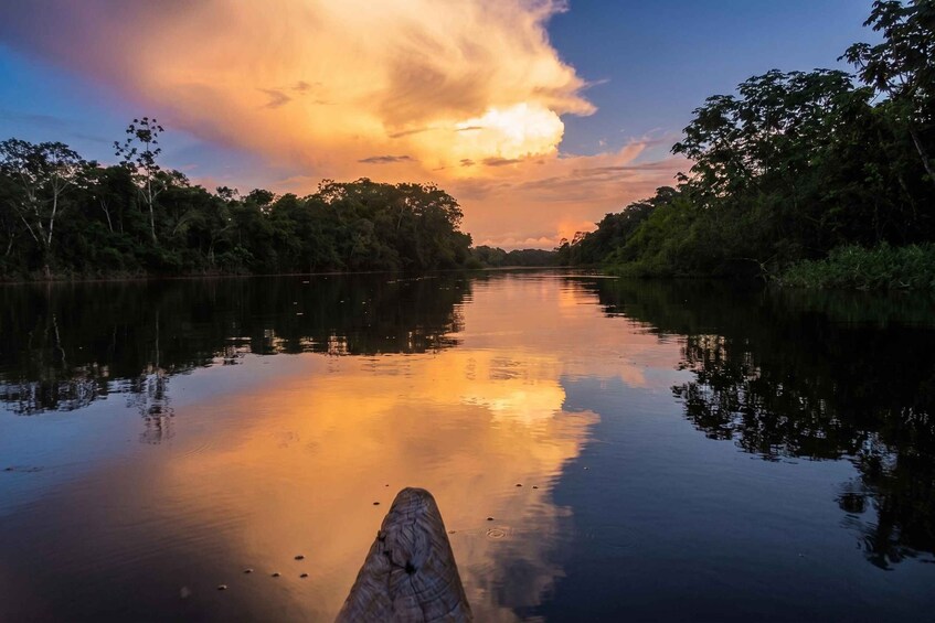 Ein ruhiger Fluss, flankiert von üppiger Vegetation, spiegelt den Abendhimmel wider. 1