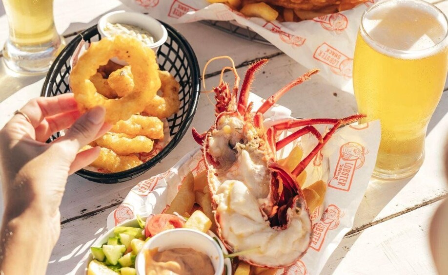 A lobster tail, onion rings, and a glass of beer on a table. 5