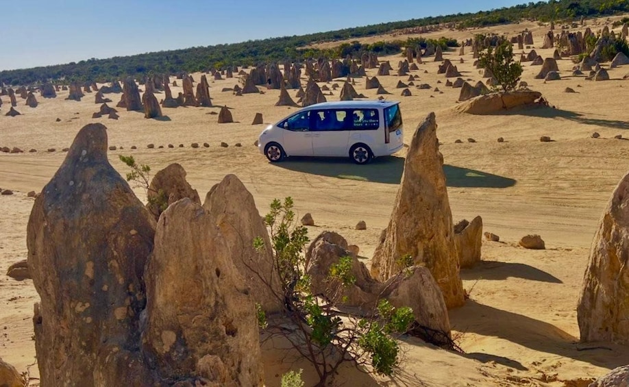 A white van parked in a desert landscape with numerous rock formations. 1
