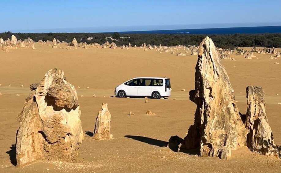 A white van parked among rock formations in a desert landscape. 2