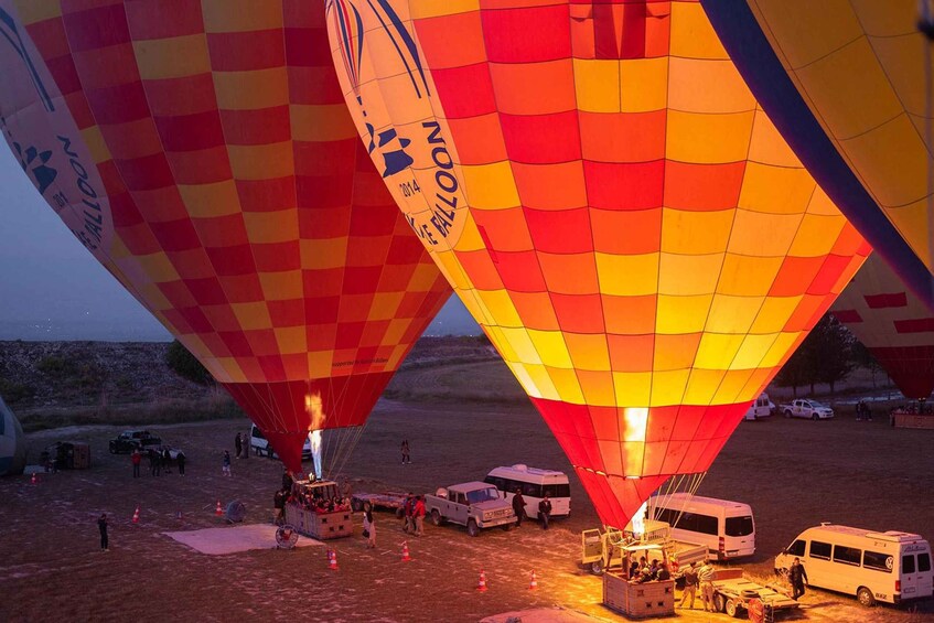 Hot air balloons with people and vehicles on a field. 2