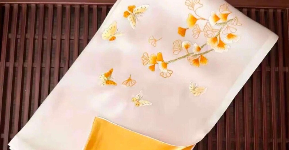 A white fabric with orange and yellow floral embroidery. 3