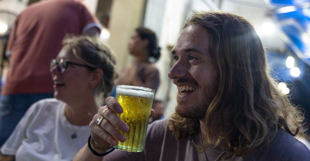 A person holding a glass of beer. 3