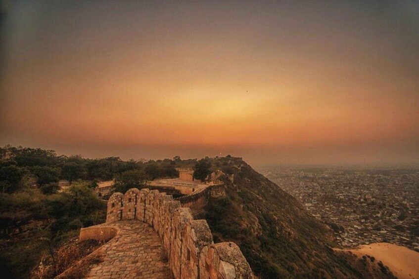 A stone pathway leading up a hill with a cityscape in the background. 2
