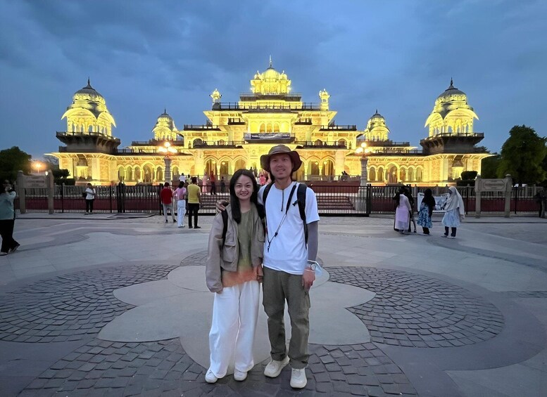 A couple posing in front of a brightly lit historical building with domes and arches. 1