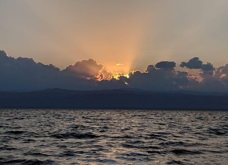 A sunset over a body of water with mountains in the background. 1
