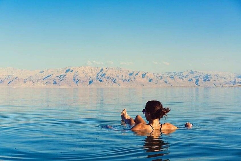 A person swimming in a large body of water with mountains in the background. 4