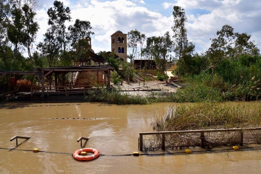 A flooded area with a wooden bridge, a lifebuoy, and a tower in the background. 2