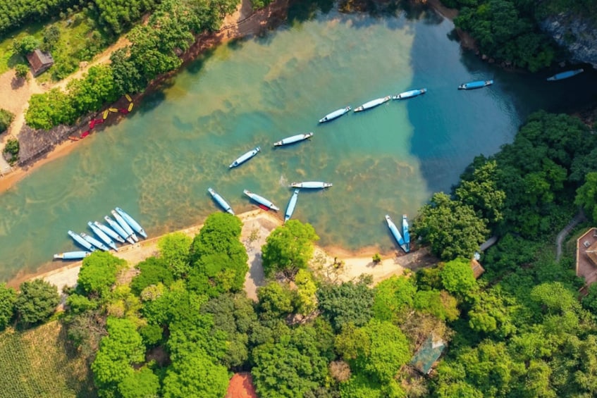 An aerial view of a river with several boats docked along the shore, surrounded by dense greenery. 2