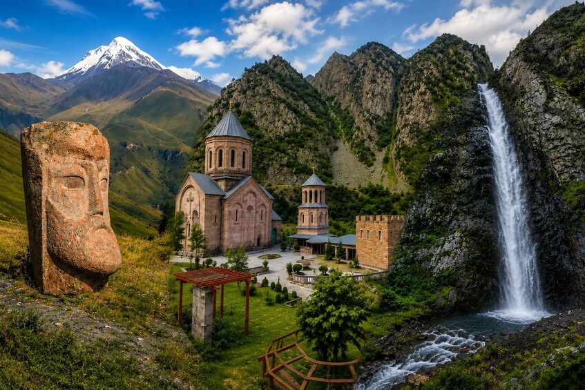 A church, a stone face, and a waterfall in a mountainous landscape. 1