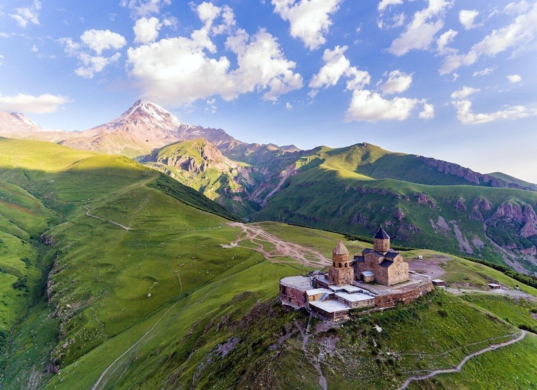 A mountainous landscape with a historic stone church on a hill. 4