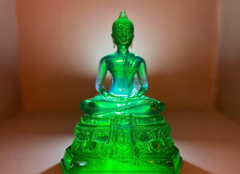 A green glass Buddha statue with intricate carvings on its base. 4