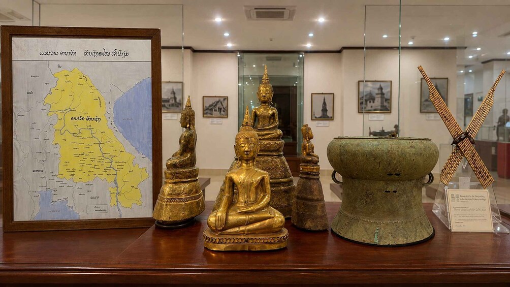 A map, golden Buddha statues, and a green urn with inscriptions. 1