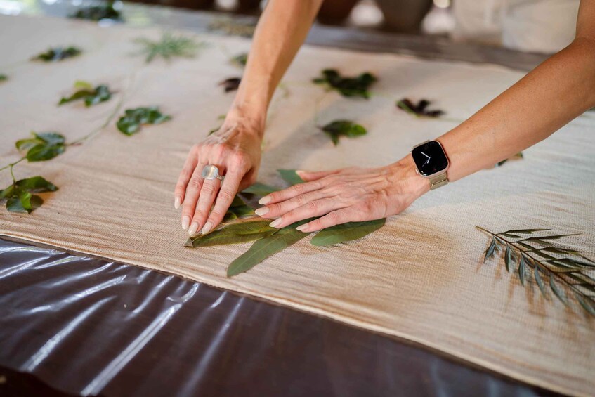 Hands arranging leaves on a fabric-covered table. 5