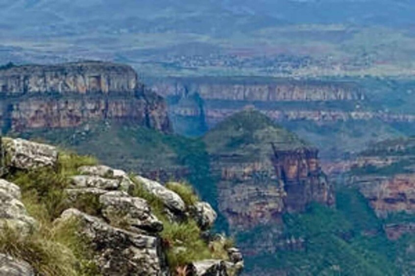 A canyon with layered rock formations and sparse vegetation. 2