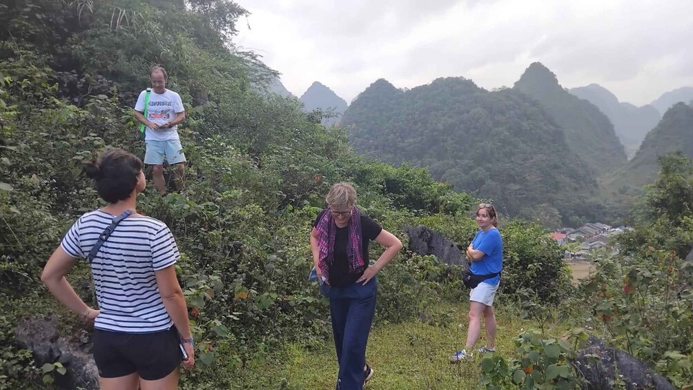 A group of people hiking in a mountainous area with lush greenery and distant peaks. 4
