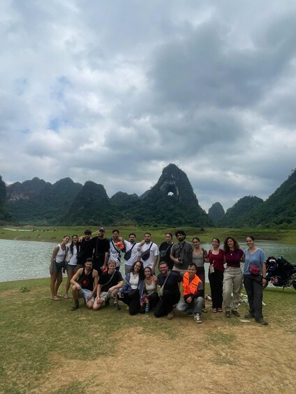 A group of people posing by a lake with mountains in the background. 5