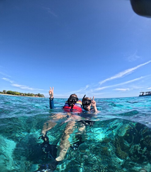 Two people snorkeling in clear blue water with a boat in the background. 5