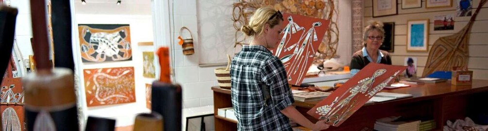A person working on a painting in an art studio with various artworks on the walls. 5