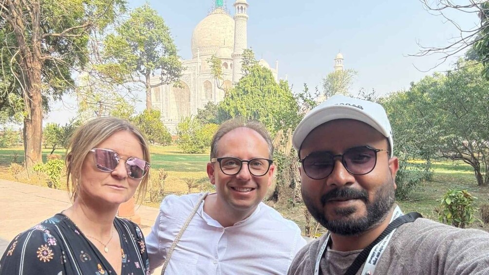 Three people standing in front of a large historical building with domes and minarets. 2