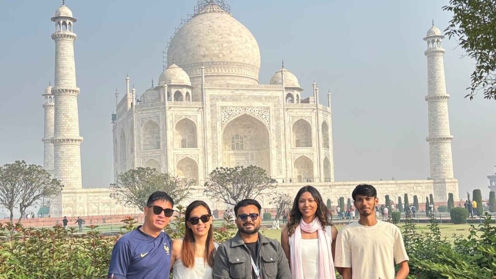The Taj Mahal with four people standing in front. 5