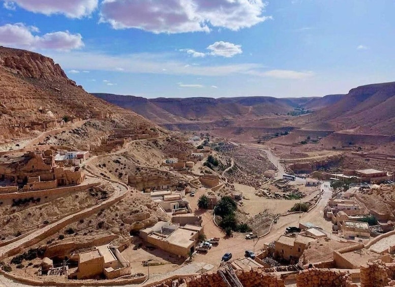 A desert landscape with a small settlement, winding roads, and distant hills. 3