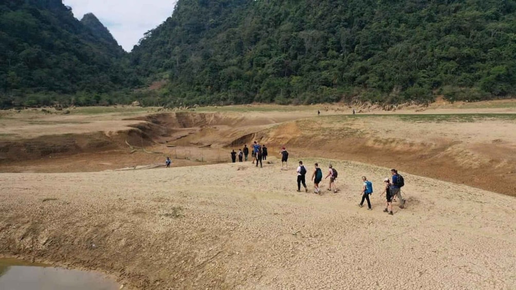 A group of people hiking in a dry, hilly landscape with sparse vegetation. 3