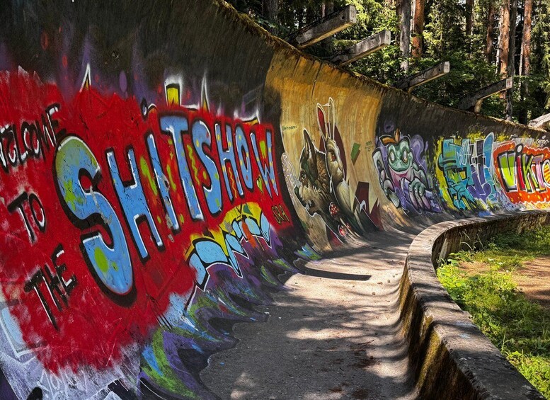 A graffiti-covered concrete wall with a skateboarding ramp. 1
