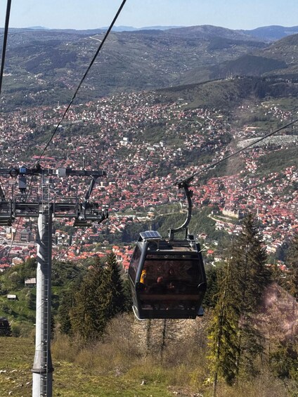 A cable car ascending a mountain with a town below. 2