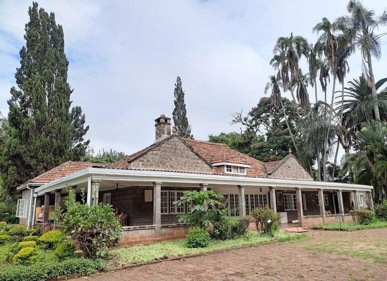 A large stone house with a tiled roof, surrounded by lush greenery and tall trees. 2